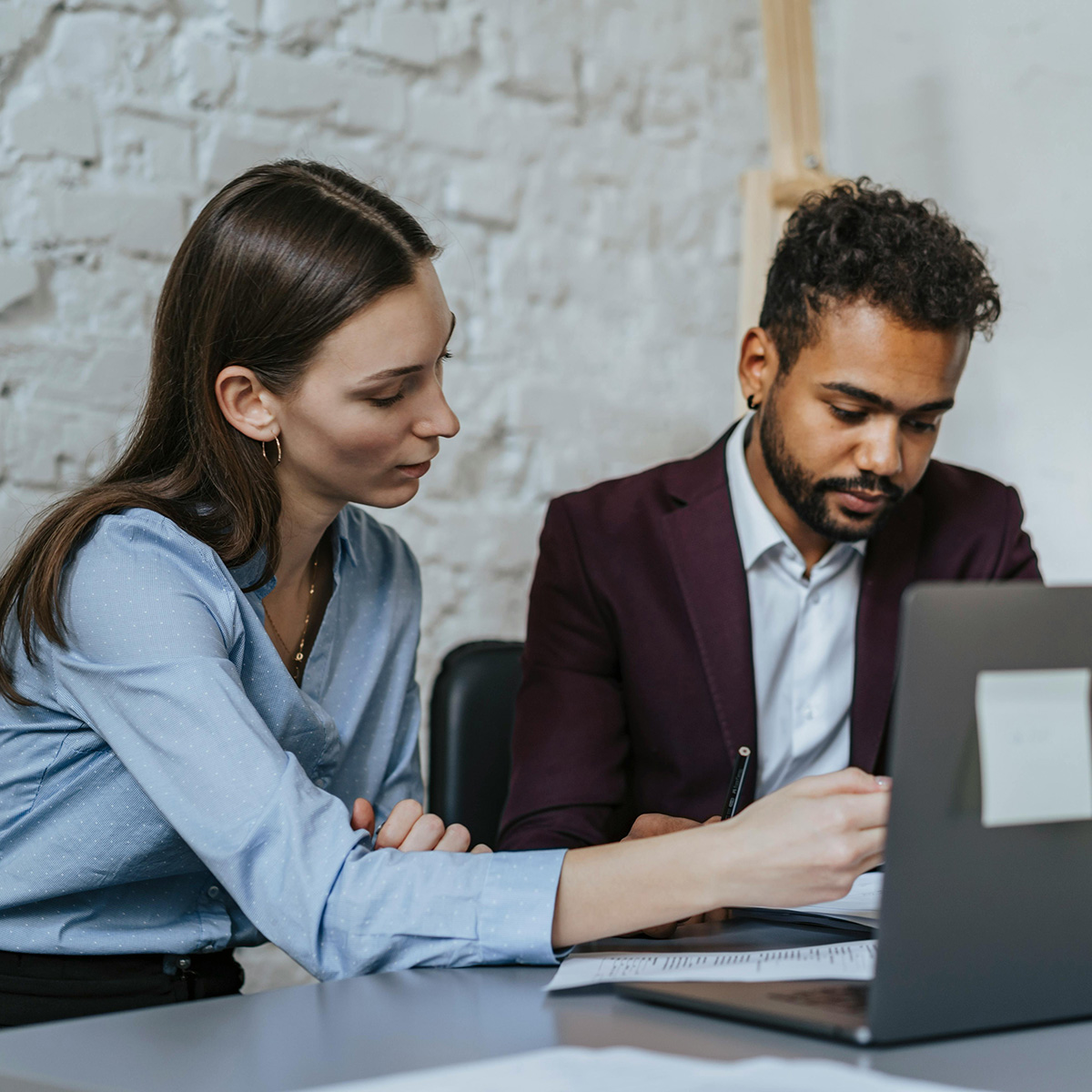 Two people working together on their computers at a meeting. 